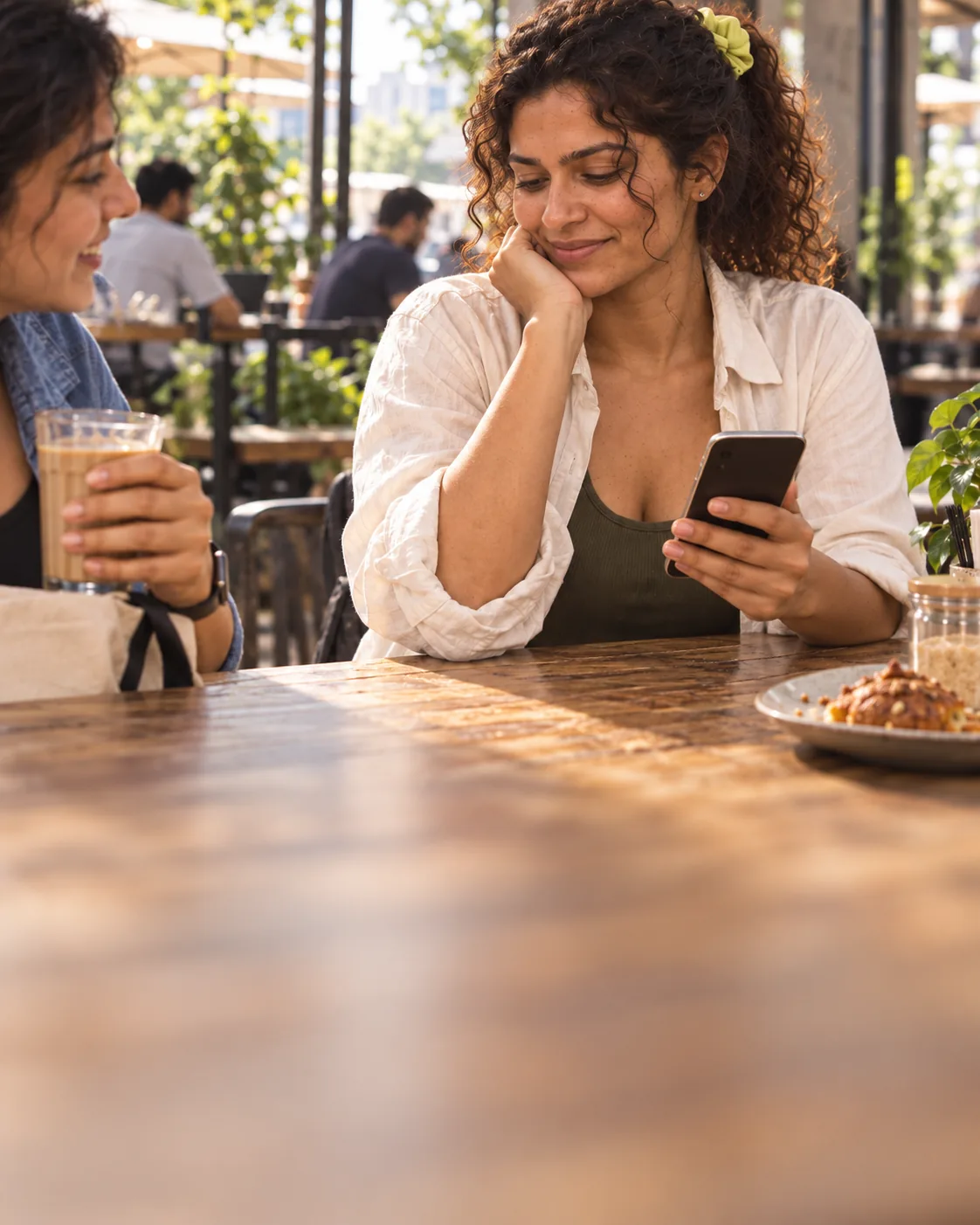 Smiling at a message on her phone at a café table
